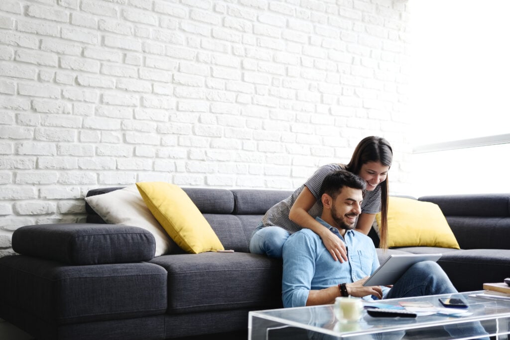 Couple relaxing on a sofa while looking at a tablet together.