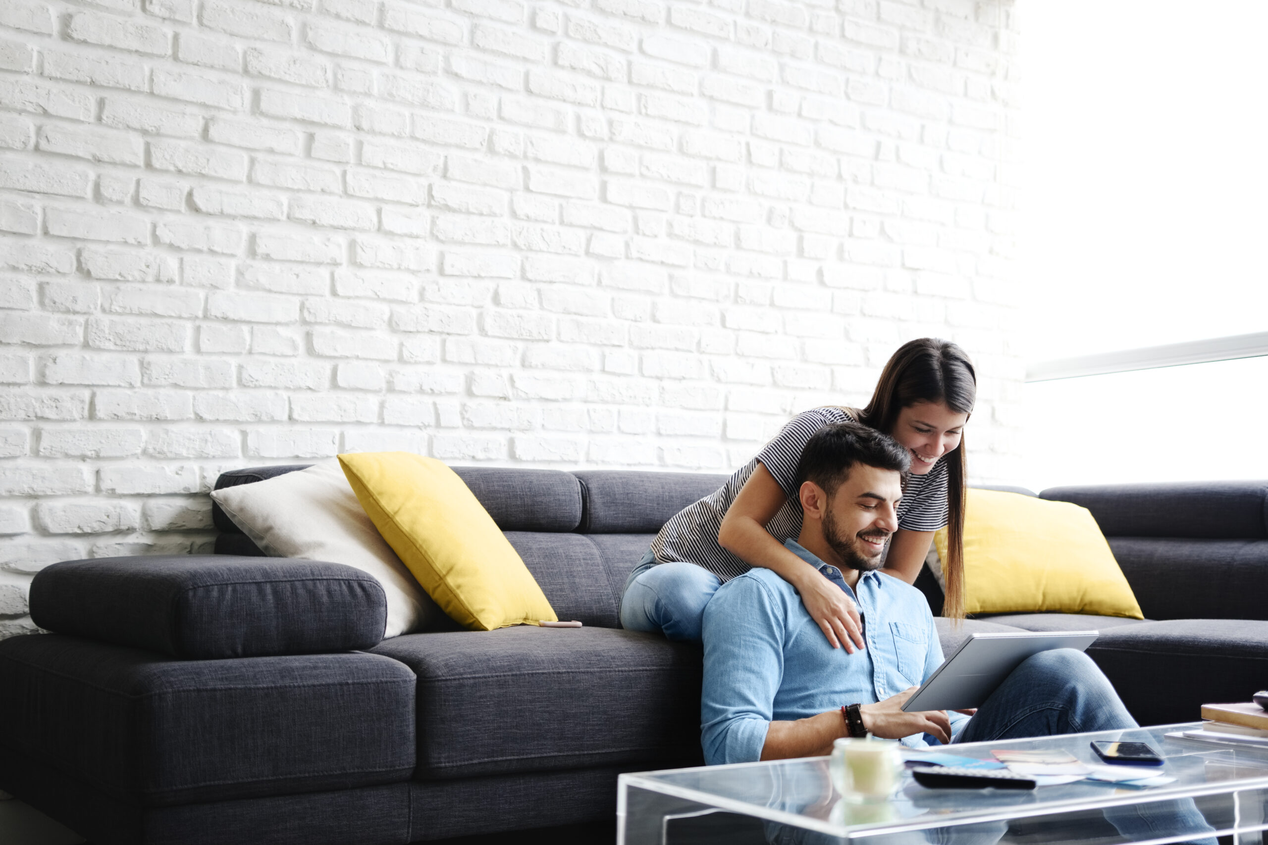 Couple relaxing on a sofa while looking at a tablet together.