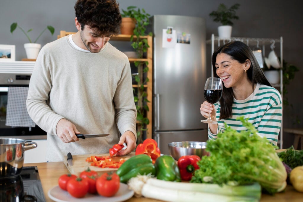 Couple preparing food in a modern kitchen with fresh vegetables.