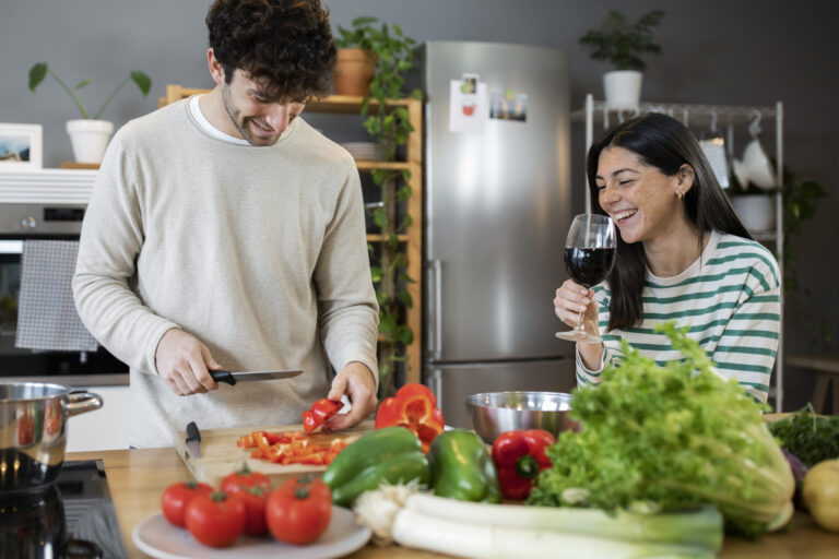 Couple preparing food in a modern kitchen with fresh vegetables.